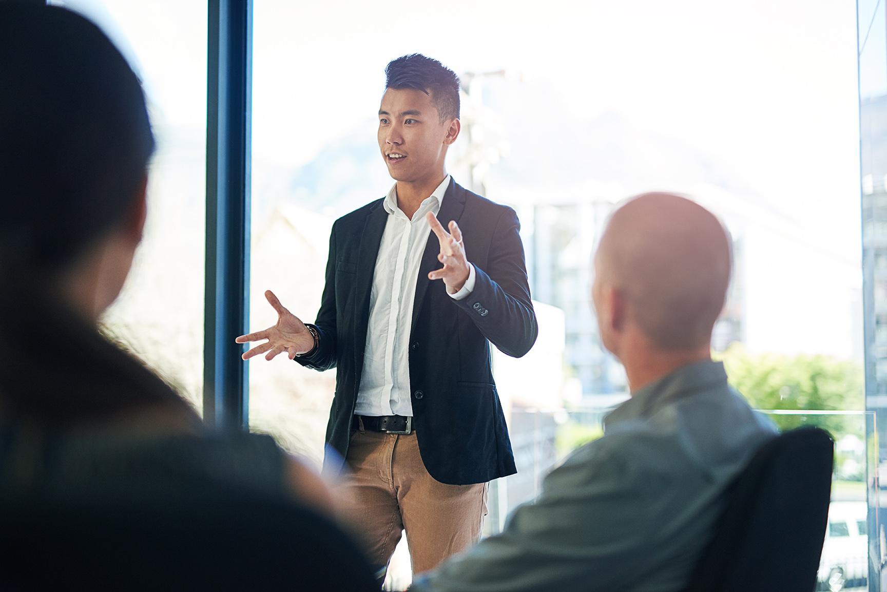 Young business professional speaking in front of business partners.